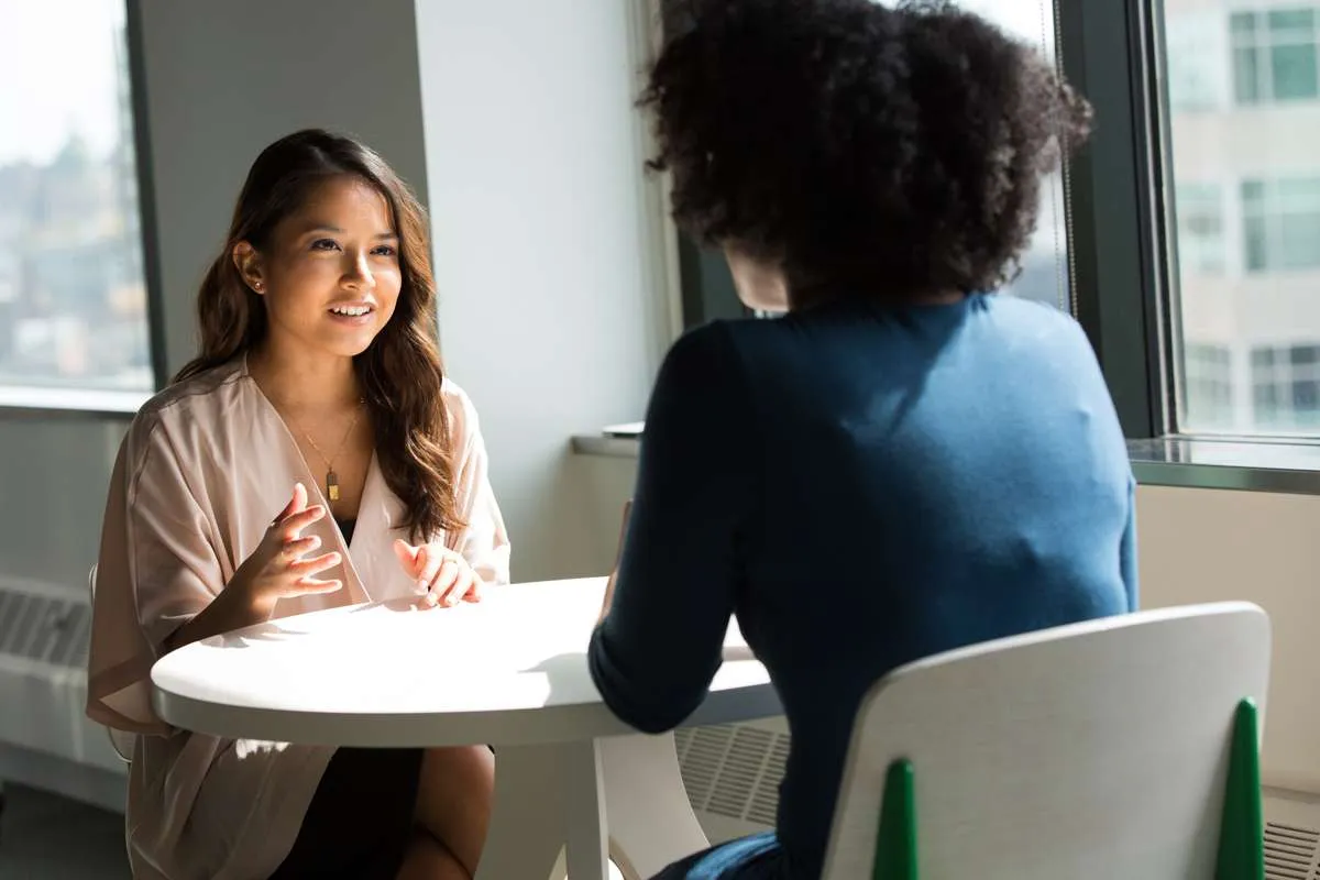 a therapist counseling a patient at a table. they are face to face.