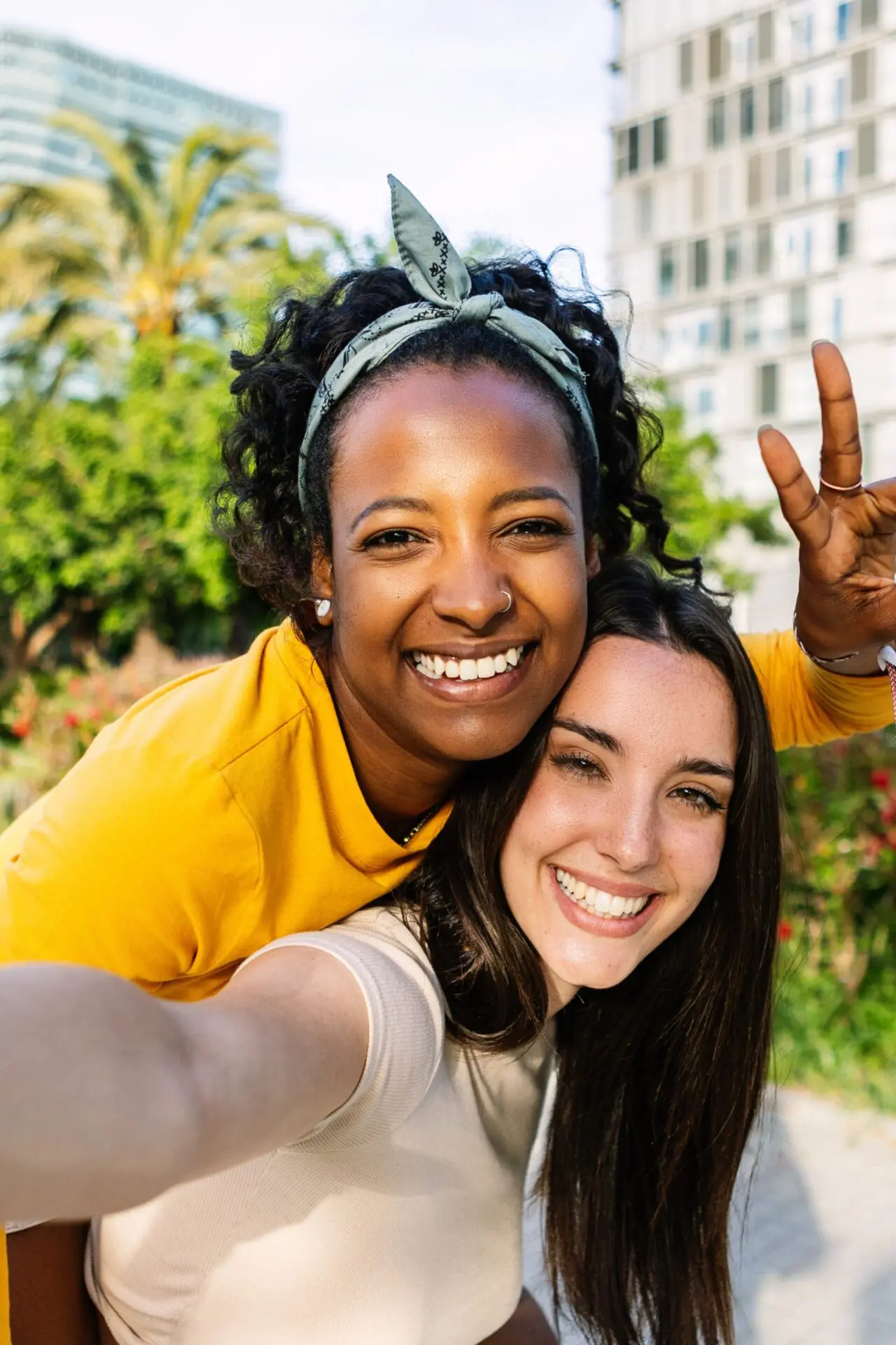 Two multi ethnic female friends taking self portrait with mobile phone outdoors